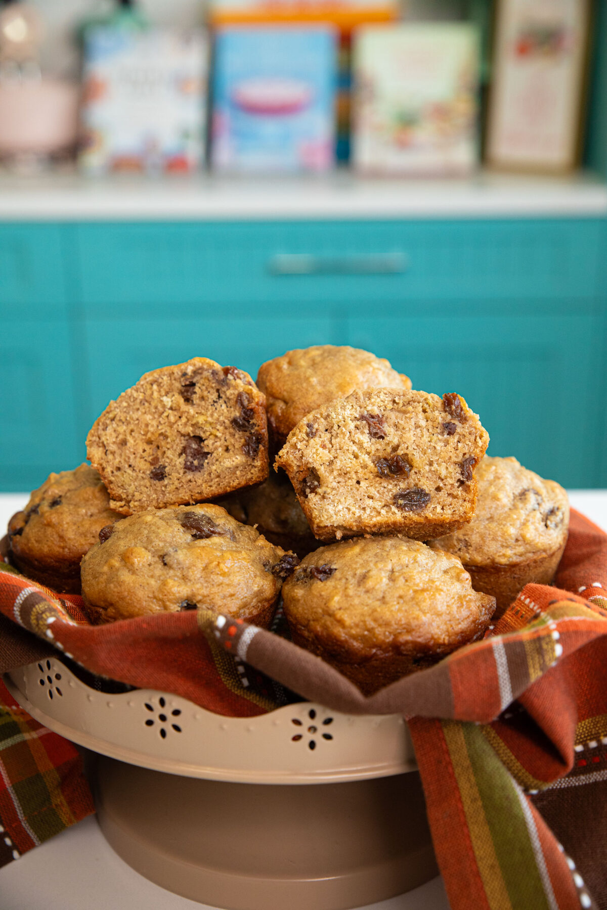 cinnamon raisin oat bran muffins on a orange brown cloth one cut in half