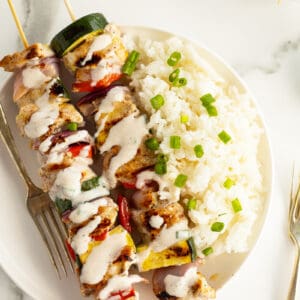 turkey kebabs on a white plate with rice